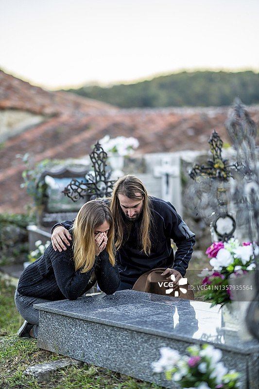 男子在墓地墓碑旁安慰女子图片素材