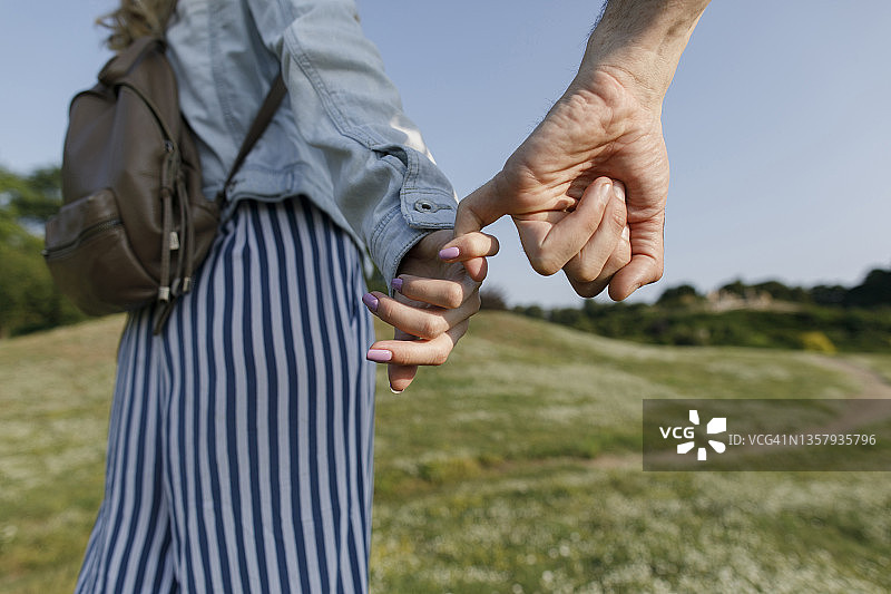 女人与男友在草地上牵手散步图片素材