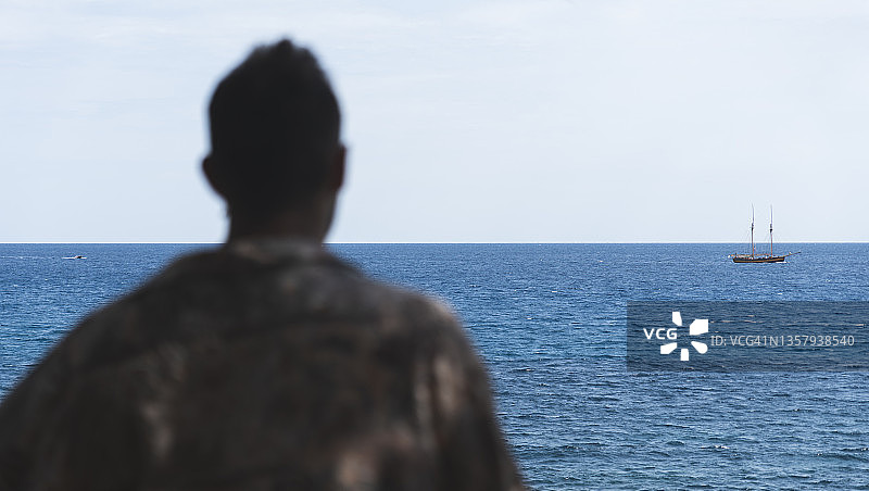 男人看着田园诗般的蓝色大海图片素材