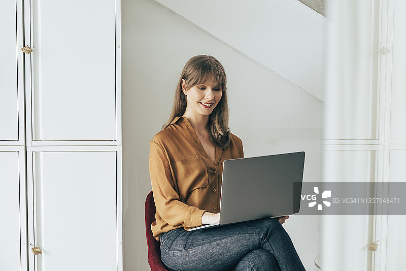 使用笔记本电脑工作的微笑女商人图片素材