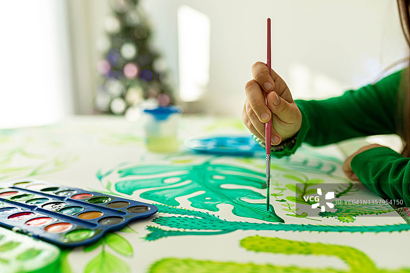 女孩用画笔和水彩在纸上绘画图片素材