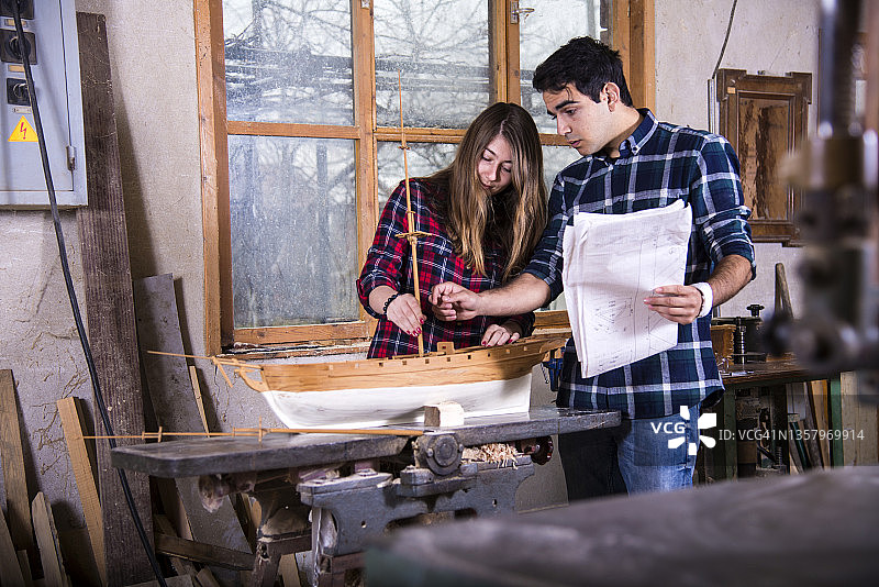 年轻情侣在工作室制作船模图片素材