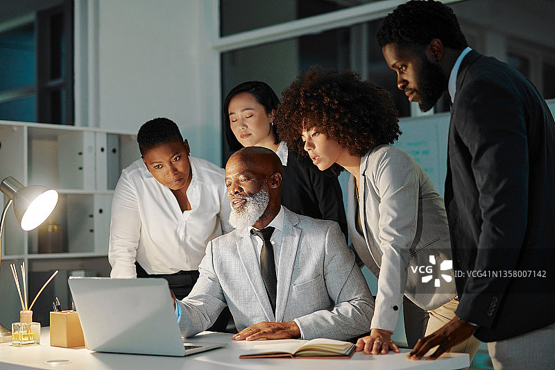 一群商人在晚上在办公室里用笔记本电脑一起工作图片素材