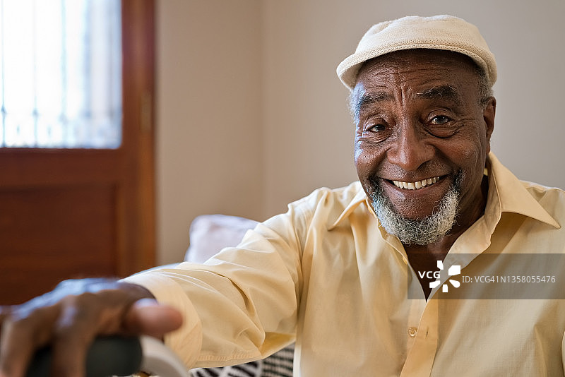 笑容满面的戴帽子老年男人在家中图片素材