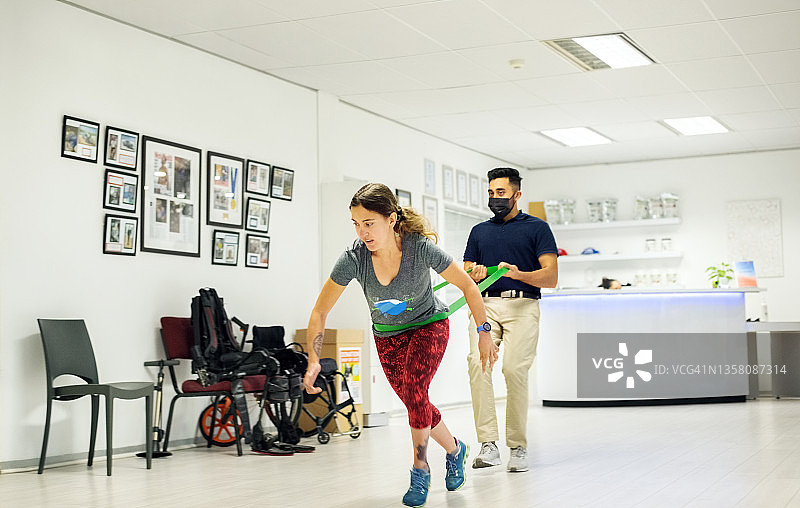 脑瘫女人与教练用阻力带锻炼图片素材