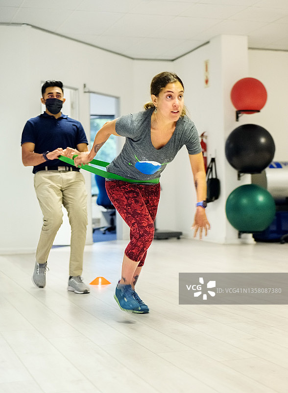 患有脑瘫的女人在康复中心与健身教练一起使用阻力带进行锻炼图片素材
