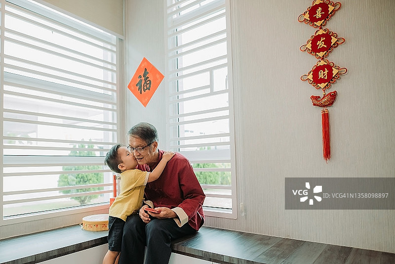 华人孙子新年期间在客厅拥抱祖父图片素材