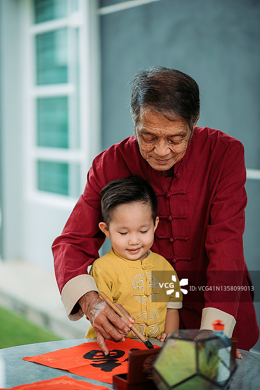 中国爷爷和孙子在院子里写中国书法，喜迎新年图片素材