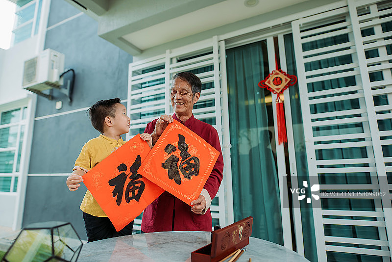 中国新年期间，在院子里手持中国书法的亚洲祖孙图片素材