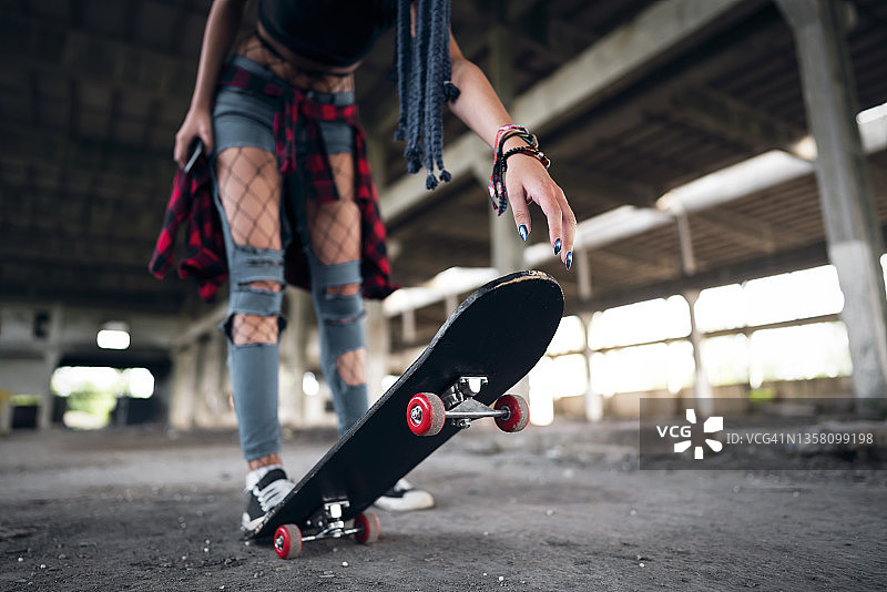 年轻女子在废弃工业建筑中玩滑板图片素材