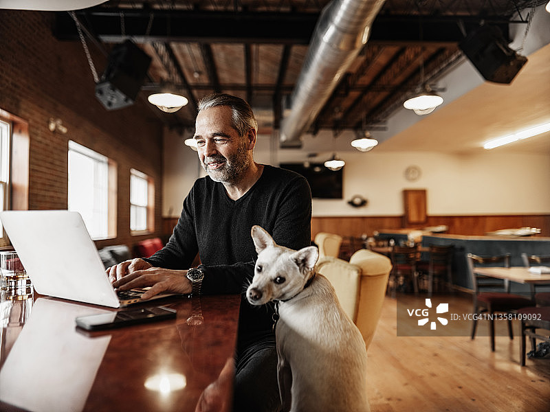 小酒吧老板和他的小狗一起工作图片素材