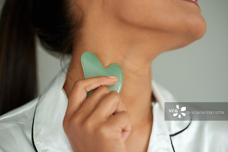 美丽的女人使用刮痧工具特写图片素材