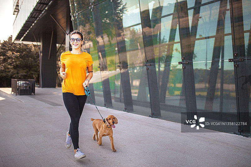 年轻漂亮的女孩在城市里遛狗图片素材