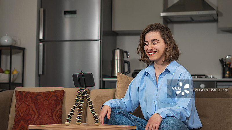 年轻女视频博主在家中沙发上直播，与粉丝聊天图片素材