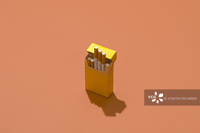 珊瑚色背景上的黄色香烟盒图片素材