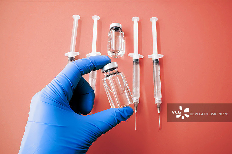 戴手套的手在橙色背景上拿着医疗药瓶图片素材