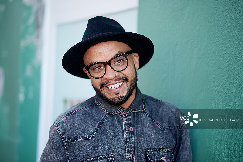 英俊时尚的年轻男子在绿色墙壁前摆姿势的照片图片素材