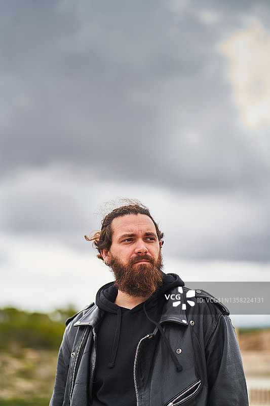 多云天空下站在自然环境中的络腮胡男人图片素材