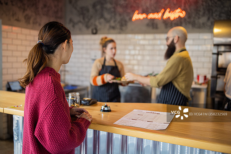 快餐店的同事为女顾客提供她订购的三明治图片素材