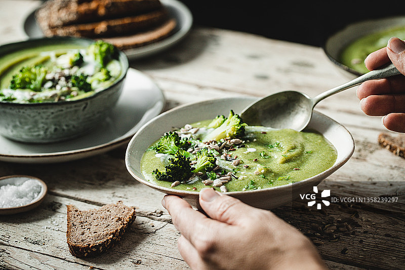 用勺子吃新鲜西兰花汤的人图片素材