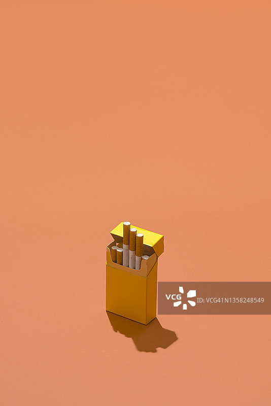 珊瑚色背景上的黄色香烟盒图片素材