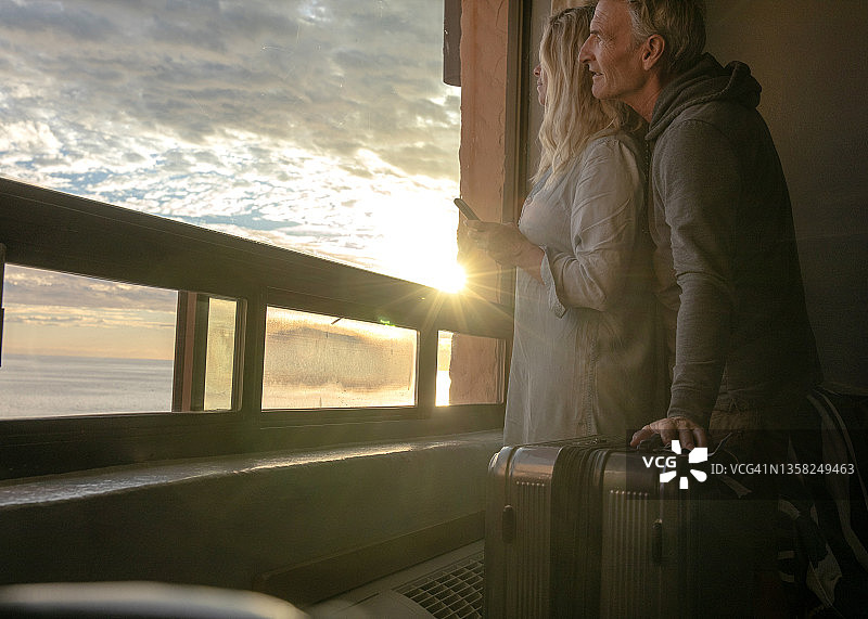 情侣在窗边放松，俯瞰海滩图片素材