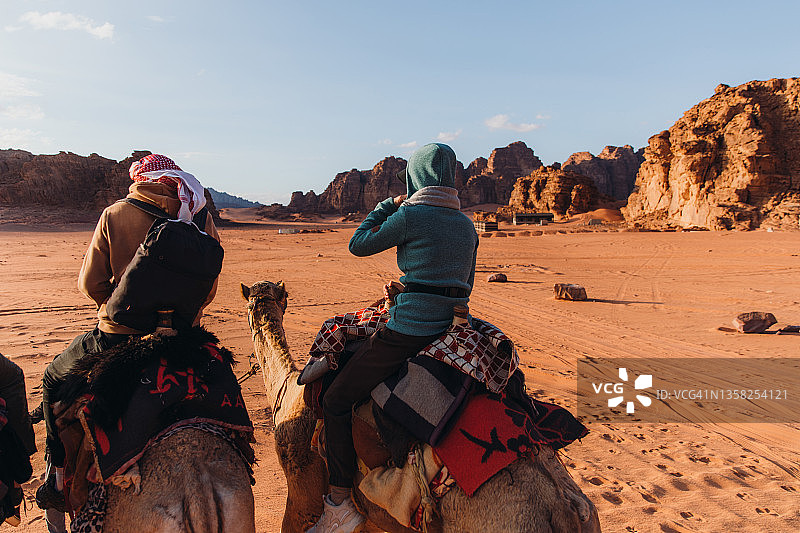 朋友们骑着骆驼在瓦迪拉姆沙漠探索，欣赏日落美景图片素材