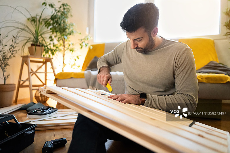 专注的白人男子在家组装家具图片素材