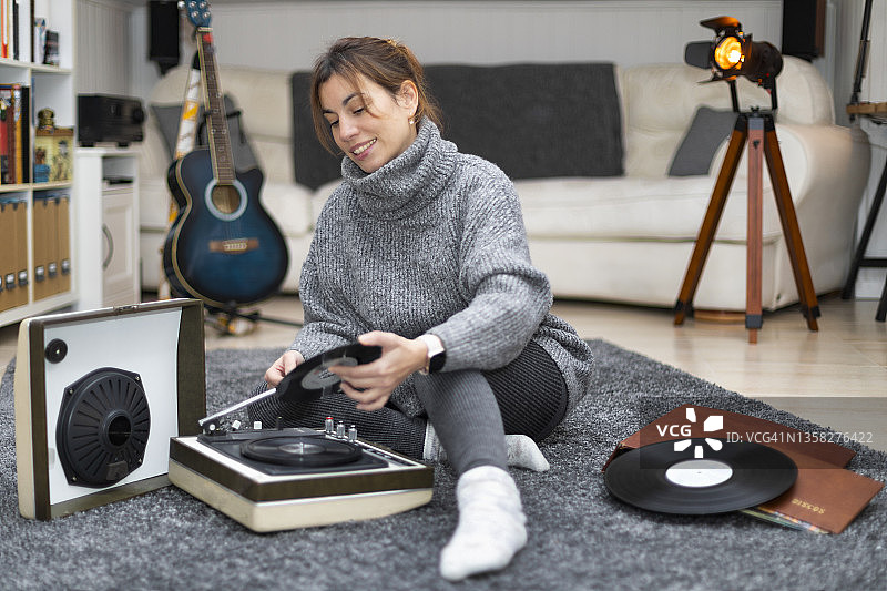 女人坐在地毯上听黑胶唱片图片素材