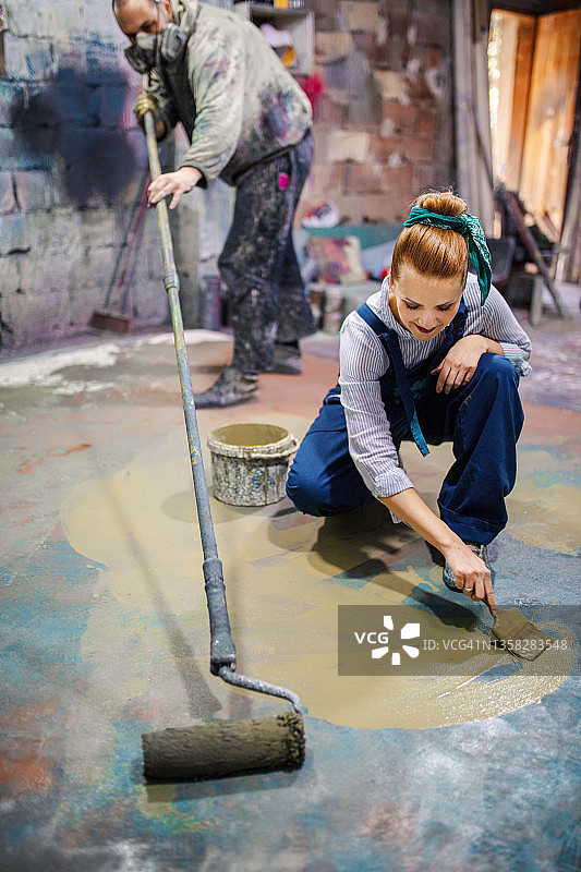 男女艺术家朋友在工作室的地板上绘画图片素材