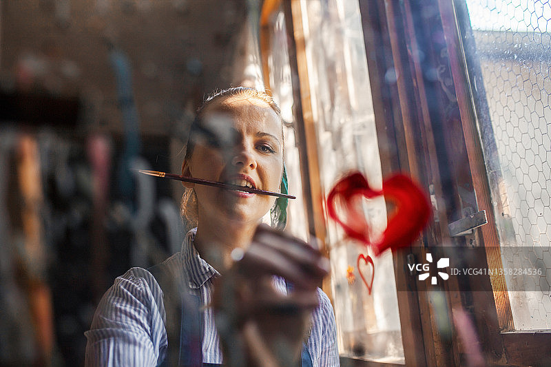 艺术家在乡村房间的窗户上绘画图片素材