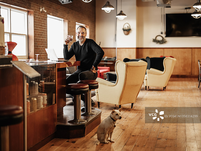 小酒吧老板和他的小狗一起工作图片素材