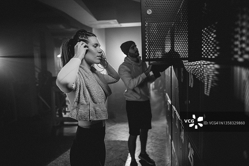 两位运动员在训练前将包放入健身房更衣柜图片素材