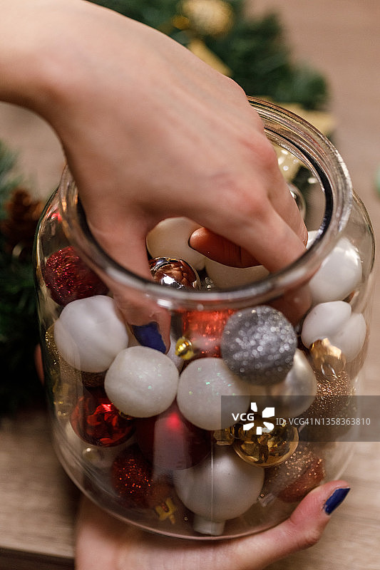 女人在玻璃罐中添加闪光装饰品，作为圣诞节的装饰图片素材