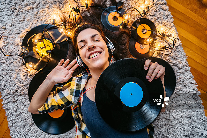 年轻女人躺在地板上听音乐图片素材