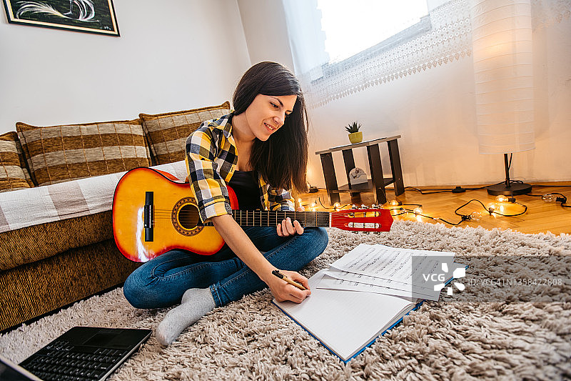 在卧室里弹吉他的年轻女子图片素材