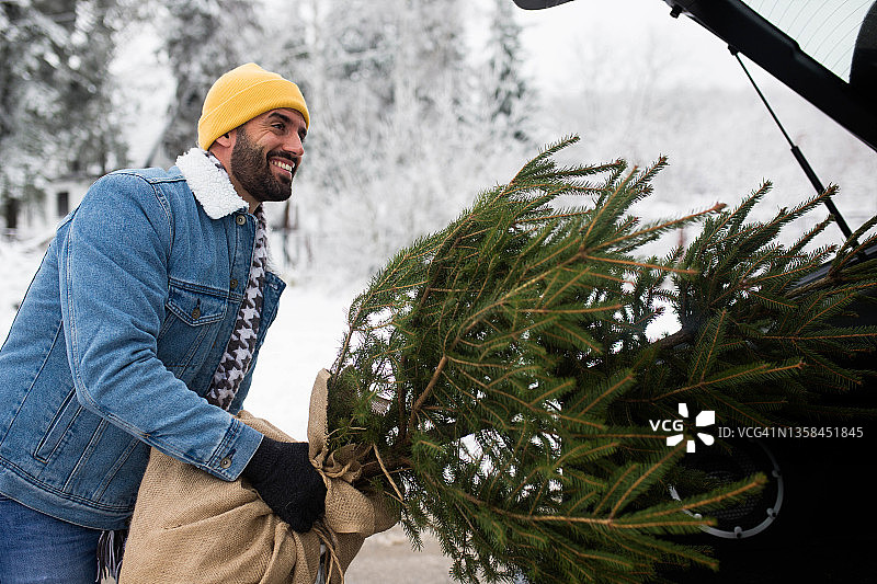 英俊的男人挑选完美的圣诞树图片素材