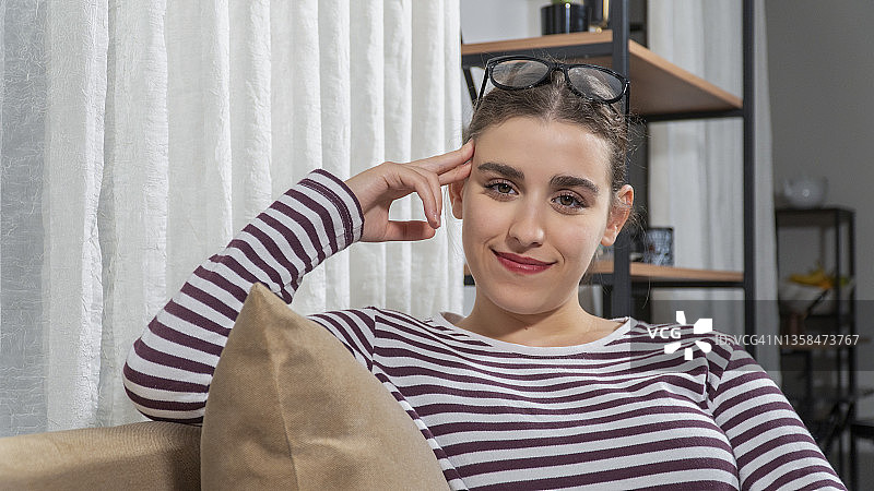 一位看着镜头的年轻女子，她戴着眼镜，面带微笑图片素材