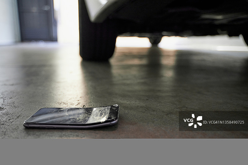汽车在地板上碾压智能手机图片素材