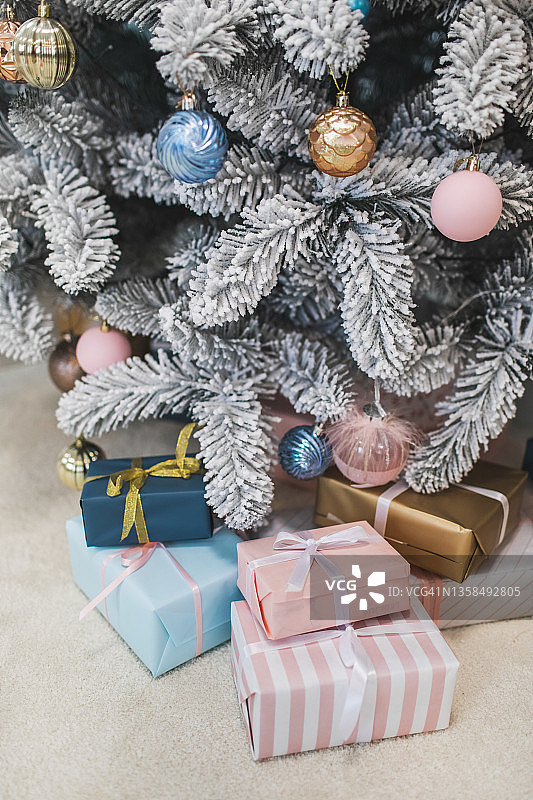 房间里圣诞树旁的松软地毯上放着漂亮的圣诞礼品盒。图片素材