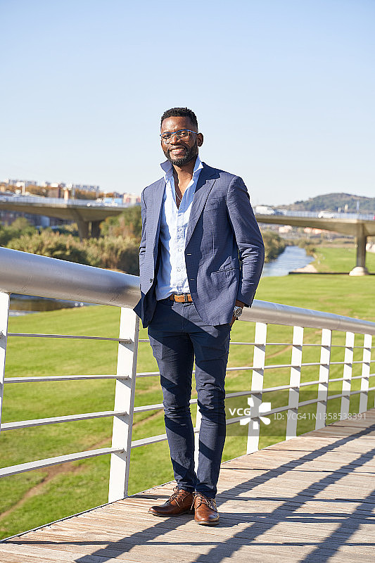 身穿蓝色西装，双手插在裤子口袋里看着镜头的男人的正面视图图片素材