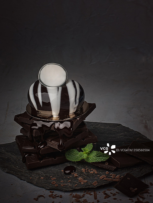 现代慕斯蛋糕的食物摄影，巧克力釉面，深灰色背景特写图片素材