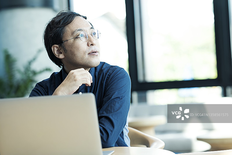 日本企业家在偏远办公室使用笔记本电脑思考商业计划图片素材