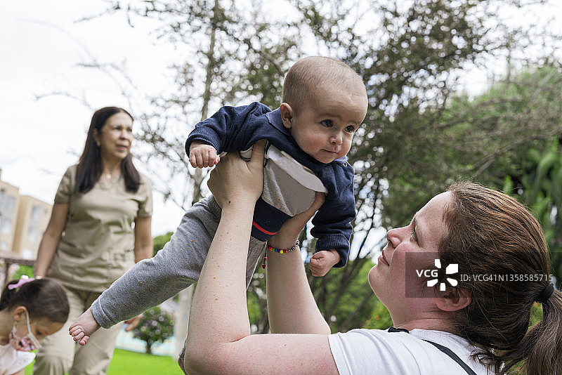 儿科理疗师为婴儿患者进行治疗，母亲在一旁协助学习图片素材
