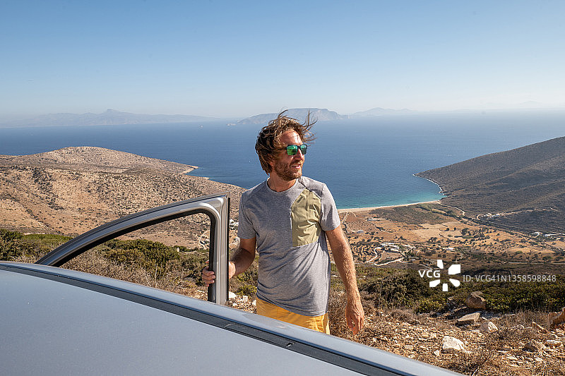 下车观看全景的年轻男人，海滩公路旅行概念图片素材