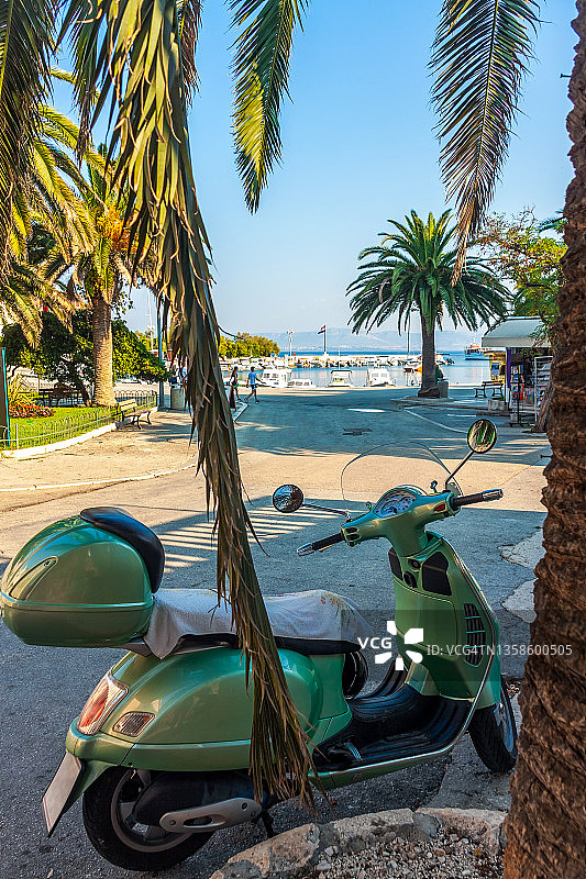 停在克罗地亚布拉奇岛苏佩塔尔港棕榈树旁的轻便摩托车图片素材