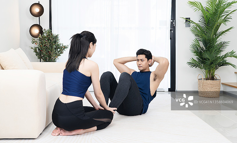 在家中客厅一起锻炼的快乐亚洲夫妇图片素材