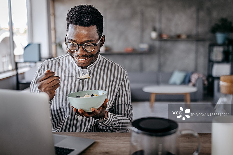 男人吃早餐并使用笔记本电脑图片素材