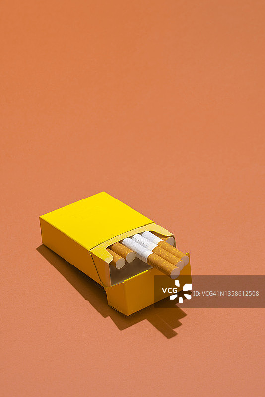 珊瑚色背景上的黄色香烟盒图片素材