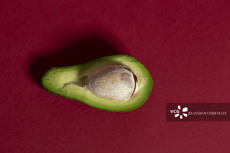 红色背景下的牛油果切片特写图片素材